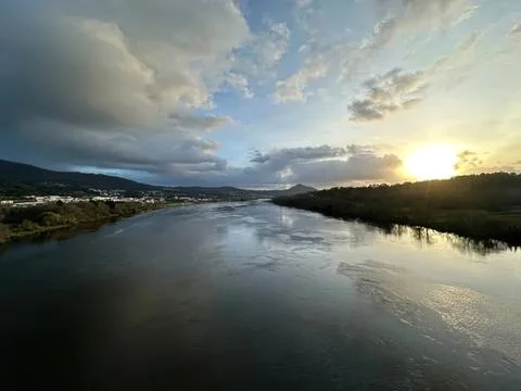 Scenic river view at sunset with cloudy sky and mountains Stock Photos