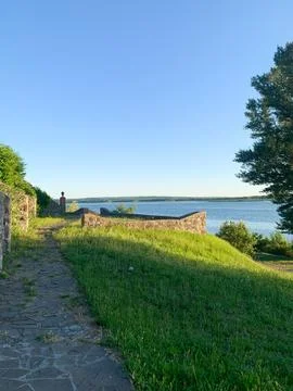 Scenic river view with a walking path and lush greenery under clear skies Stock Photos
