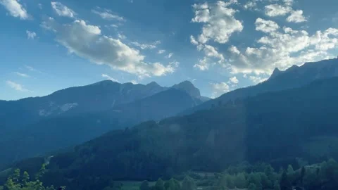 Scenic road through green alpine mountains with a lake and clouds in the summer  Stock Footage 340341499