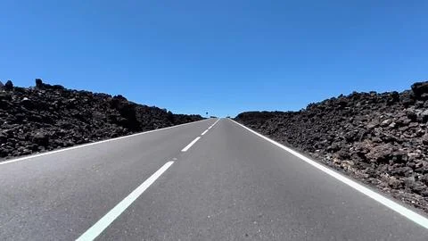 A Scenic Roadway Cutting Through a Dramatic Volcanic Landscape Beneath a Cl.. Stock Photos