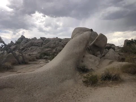 Scenic Rock Formation Under Dramatic Clouds in a Desert Landscape Stock Photos