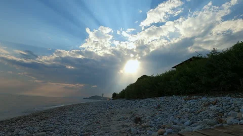 Scenic rocky beach with sun rays breaking through clouds Stock Footage 297372845