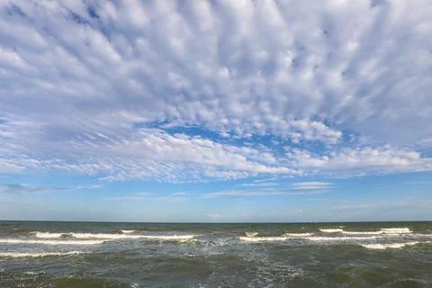 Scenic seascape with waves and patterned fluffy clouds in blue sky at Barri.. Fotos Stock