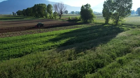 Scenic Spring Fields: Colorful Parcels and Tractor Cultivating Soil for Stockbeeldmateriaal 274726632