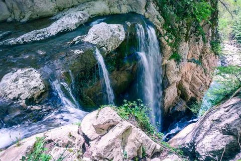 A scenic stream of a waterfall falling among a rocky gorge. Agur river. Stock Photos