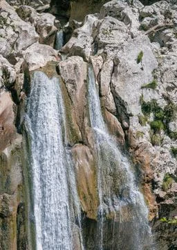 A scenic stream of a waterfall falling among a rocky gorge on the Agur river. Stock Photos