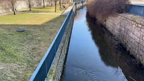 A Scenic Streamside View Featuring Charming Fencing and Lush Green Grass Al.. Stock Photos
