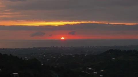Scenic sun setting over the ocean with cityscape silhouette Stock Footage 345754225