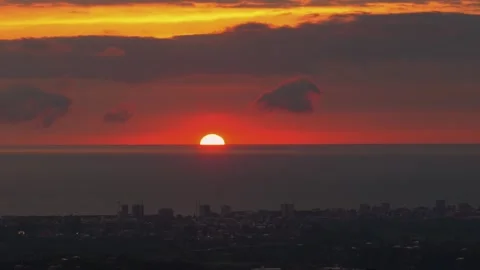 Scenic sun setting over the ocean with cityscape silhouette Stock Footage 346778883