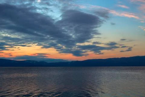 A scenic sunset with a black cloud in the shape of a flying figure over Lake. Stock Photos