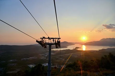 Scenic sunset landscape view with a cable car tower over sea, mountains Stock Photos
