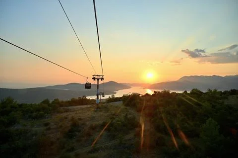 Scenic sunset landscape view with a cable car tower over sea, mountains Stock Photos