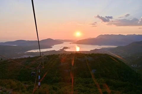 Scenic sunset landscape view with cable car cables over sea, mountains, and city Stock Photos