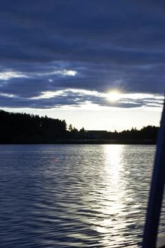 Scenic sunset over lake with dramatic cloudy sky and sun rays reflecting on wate Stock Photos