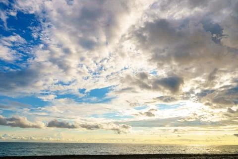 Scenic sunset over sea with dramatic sunlit clouds in sky Foto stock