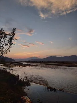 Scenic sunset reflection over calm lake water and mountain horizon Stock Photos