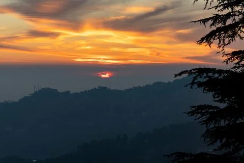 Scenic sunset view with layered clouds and city silhouette Stock Photos