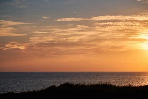 Scenic sunset view over the calm sea with warm golden light casting across .. Stock Photos