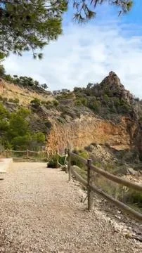 Scenic trail path with trees and rocky hills in the background Stock Photos