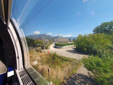 Scenic Train Window View Over Countryside Village and Mountains on Sunny Su.. Stock Photos