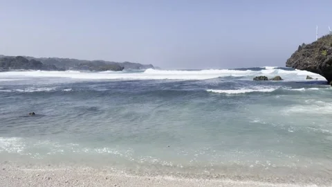 Scenic Tropical Beach with Rolling Ocean Waves and Rocky Cliff Stock Footage 338370522