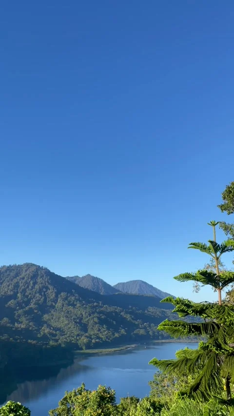 Scenic tropical mountain reflection on calm lake with clear blue sky in Bali Stock Footage 336446566