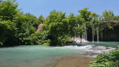 Scenic Turquoise Waterfall Cascading into River in Lush Green Forest 動画素材 337699537