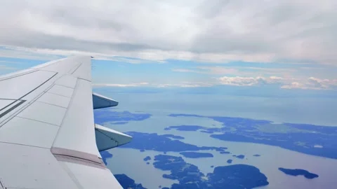 Scenic view from airplane window showcasing wing and distant islands Stock Footage 317877733