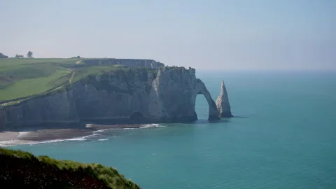 Scenic view of amazing rock arch in Etretat, sea waves crash on sandy shore on Video stock 242425128