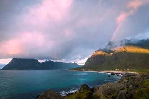 Scenic view on beach, rainbow and mountains against the sunset sky Photos