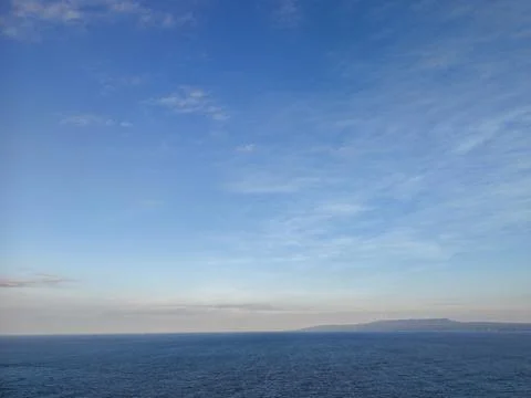Scenic View of Calm Ocean Under Clear Blue Sky with Distant Island 库存照片