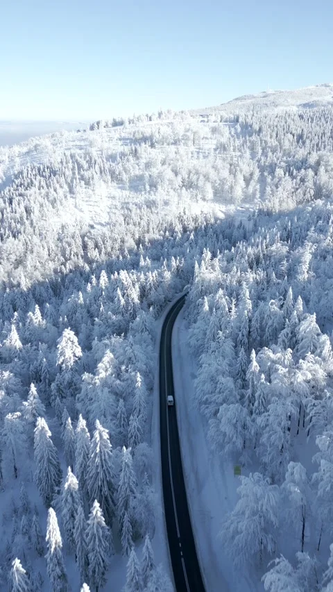 Scenic view of a car driving through the snowy winter mountains on sunny day Stock Footage 259633124