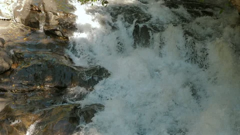 Scenic view of cascading waterfall over rocky terrain, with frothy Stock Footage 280178824