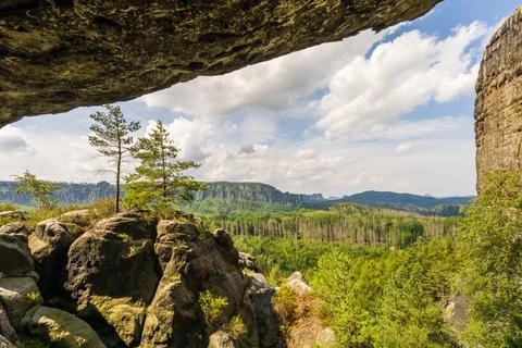 Scenic view from cave of sandstone cliffs rising above pine forest in Saxon.. Stock Photos
