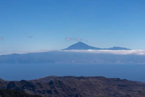 Scenic view on cloud covered volcano mountain peak Pico del Teide on Teneri.. Stock Photos