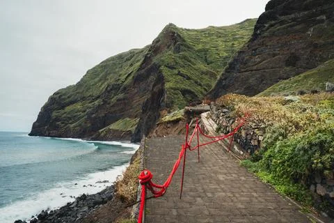 Scenic view of a coastal path alongside majestic green cliffs, ocean waves, a Stock Photos