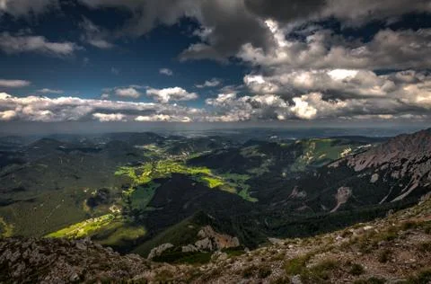 Scenic view with dark, blue, cloudy, sky with rubble fields and green forest Stock Photos