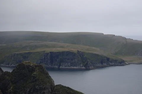 Scenic view of dramatic coastal cliffs and the sea on a cloudy and foggy summ Stock Photos
