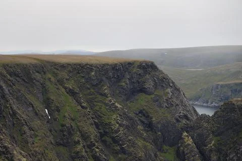 Scenic view of dramatic coastal cliffs and the sea on a cloudy and foggy summ Stock Photos