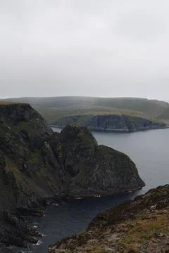 Scenic view of dramatic coastal cliffs and the sea on a cloudy and foggy summ Stock Photos