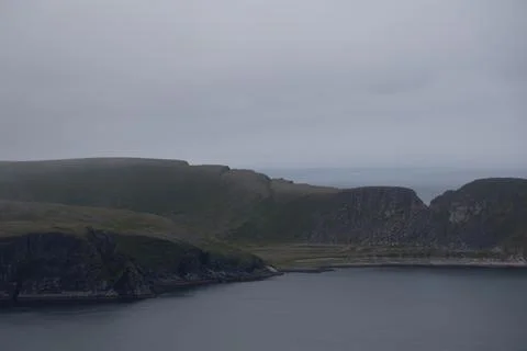 Scenic view of dramatic coastal cliffs and the sea on a cloudy and foggy summ Stock Photos