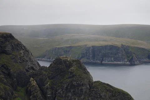 Scenic view of dramatic coastal cliffs and the sea on a cloudy and foggy summ Stock Photos