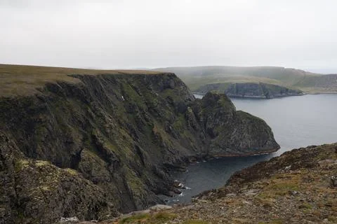 Scenic view of dramatic coastal cliffs and the sea on a cloudy and foggy summ Stock Photos