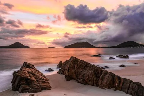 Scenic view of a dramatic sunrise over the ocean with rugged rocky beach Stock Photos