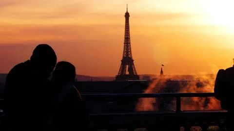 Scenic view of Eiffel tower against orange sunset sky with silhouettes of people Foto stock