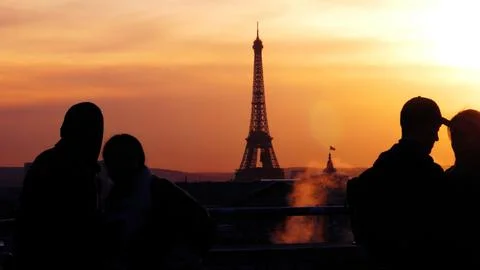 Scenic view of Eiffel tower against orange sunset sky with silhouettes of people Foto stock