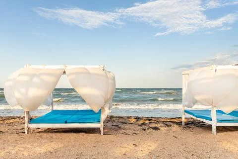 Scenic view empty white beach wooden canopies cabanas with white curtain blowing Stock Photos