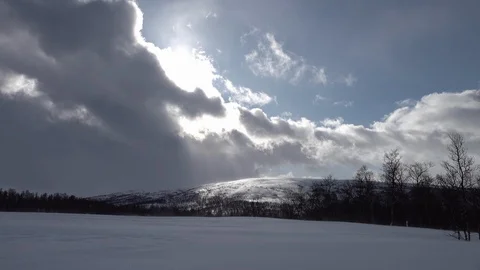 Scenic view at fast moving clouds with drifting snow over mountains and field Stock Footage 130078979