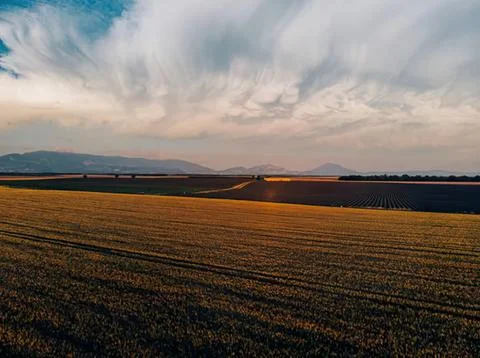Scenic view of fields with cloudy sky and distant hills Stock Photos