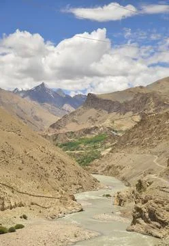 Scenic view of flowing river in between  rocky mountains with clouds in the sky  Stock Photos
